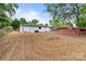 Expansive backyard view featuring freshly seeded grass, a white brick home, and mature shade trees at 1306 Klondale Ave, Kannapolis, NC 28081