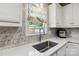 A close view of a sink and countertop in a kitchen with marble backsplash and a bright window at 1467 Alexander Rd, Rock Hill, SC 29732