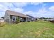 A spacious backyard featuring a covered patio, lush green lawn, and secure black metal fencing at 167 White Apple Way, Statesville, NC 28625
