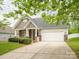 Charming home featuring a two-car garage, stone accents, and a well-maintained front lawn at 208 Fielding St, Mount Holly, NC 28120