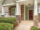 Inviting front porch with stone columns, red door and shutters, complemented by manicured landscaping at 208 Fielding St, Mount Holly, NC 28120