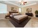Styled primary bedroom features a large bed, tray ceiling, and neutral color palette at 208 Fielding St, Mount Holly, NC 28120