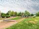 Outdoor playground with modern play structures on lush green grass with mature trees around at 208 Fielding St, Mount Holly, NC 28120