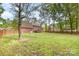 Large, grassy backyard with mature trees and a wooden privacy fence at 2514 King Arthur Dr, Monroe, NC 28110