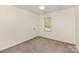 Minimalist bedroom with neutral carpet, white walls, door, and a bright window at 2514 King Arthur Dr, Monroe, NC 28110