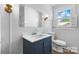 Bathroom featuring a blue vanity, toilet, large mirror, and modern fixtures, illuminated by natural light at 3015 North Center Nw St, Hickory, NC 28601