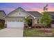 Charming brick home with a two-car garage, beautiful landscaping and a welcoming front entry at sunset at 3618 Marchers Trace Dr, Mint Hill, NC 28227