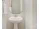 Bright powder room with a pedestal sink, decorative mirror, and fresh paint at 3618 Marchers Trace Dr, Mint Hill, NC 28227