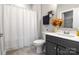 This bathroom features a shower curtain, toilet, vanity with flowers, towel and gray cabinets at 4008 Pinot Way, Fort Mill, SC 29707