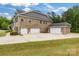 View of the rear of the home highlighting a brick exterior, multiple garages, and a well-maintained lawn at 4008 Pinot Way, Fort Mill, SC 29707