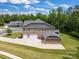View of the rear of the home highlighting a brick exterior, multiple garages, and a well-maintained lawn at 4008 Pinot Way, Fort Mill, SC 29707