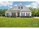 Beautiful home featuring a lush green lawn, an American flag, black shutters, and a welcoming covered front porch at 500 Chicory Cir, Matthews, NC 28104