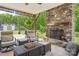 Cozy outdoor seating area featuring a stone fireplace, ceiling fan, and view of the landscaped backyard at 500 Chicory Cir, Matthews, NC 28104