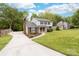 Spacious two-story home with a long driveway, lush green lawn, and mature trees providing ample shade at 616 Silversmith Ln, Charlotte, NC 28270