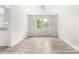 Bright, empty living room with wood-look floors and a large window overlooking a lush green yard at 616 Silversmith Ln, Charlotte, NC 28270