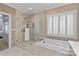 Beautiful bathroom featuring a glass-enclosed shower, soaking tub, and neutral tile at 6202 Providence Country Club Dr, Charlotte, NC 28277