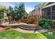 A stone patio with outdoor fireplace with tiered brick seating area and a beautiful green lawn at 6202 Providence Country Club Dr, Charlotte, NC 28277