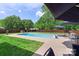 Outdoor pool area surrounded by lush green grass, patio area with umbrellas and furniture at 101 Canopy Ct, Mooresville, NC 28115