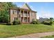 Elegant brick home with a columned porch and well-manicured lawn at 10836 Fox Hedge Rd, Matthews, NC 28105