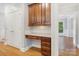 Built-in desk with wood cabinets in hallway niche, featuring hardwood floors and nearby door to another room at 10836 Fox Hedge Rd, Matthews, NC 28105