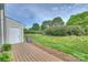 Large backyard with ample green space, complemented by trees and a wooden deck at 10943 Winterbourne Ct, Charlotte, NC 28277