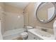 Cozy bathroom featuring a bathtub-shower combo and a decorative round mirror above the vanity at 10943 Winterbourne Ct, Charlotte, NC 28277