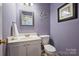 A quaint powder room features a decorative mirror and purple walls at 10943 Winterbourne Ct, Charlotte, NC 28277