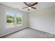 An empty room with carpet and fan features a window with a neighborhood view at 10943 Winterbourne Ct, Charlotte, NC 28277