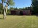 Inviting single-story home with a brick facade and a lush green lawn on a sunny day at 12016 Brief Rd, Charlotte, NC 28227