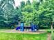 Bright, colorful blue and yellow playground equipment is surrounded by green trees and grass in this community recreation area at 13402 David Jennings Ave, Charlotte, NC 28213