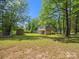 Large green backyard with mature trees, storage shed, partial fence, and house offering a serene outdoor space at 1758 Bridlewood Ct, Gastonia, NC 28054