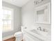 Well-lit bathroom with a white vanity, mirror, toilet, and window at 320 Evans Nw St, Concord, NC 28027