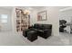Relaxing bonus room with a black leather sofa, storage ottomans, and built-in bookshelves at 341 Pleasant Hill Se Dr, Concord, NC 28025