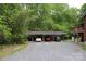 Large carport that can accommodate up to three vehicles, nestled amidst a backdrop of mature trees and lush greenery at 347 Poole Rd, Troy, NC 27371