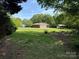 A single-story brick home with an attached garage and carport sits on a large, grassy lot with mature trees at 370 Sherrill Farm Rd, Lincolnton, NC 28092