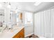 Bright bathroom features a white shower curtain, a window, and an oak vanity with a solid surface countertop at 406 S Gaston St, Dallas, NC 28034