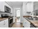 Well-lit kitchen with white cabinets, stainless steel appliances, and an open view to the playroom at 4606 Falcon Chase Sw Dr, Concord, NC 28027