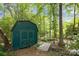 Storage shed nestled in a wooded area with green exterior and surrounding landscape at 4611 Cringle Ct, Charlotte, NC 28226