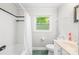 Bathroom featuring a shower-tub combo, marbled green flooring, and a bright window at 4901 White Oak Rd, Charlotte, NC 28210