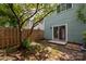 View of the fenced backyard, patio, mature shade trees, and sliding glass doors to the home at 7309 Pebblestone Dr # D, Charlotte, NC 28212