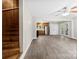 Spacious living room showcasing wood stairs and new gray floors, leading to a kitchen with stainless steel appliances at 7905 Quail Field Dr, Charlotte, NC 28227