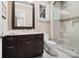 Bathroom featuring a granite-topped vanity, toilet, and a tiled shower with glass door at 8670 Arbor Oaks Cir, Concord, NC 28027