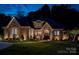 Beautifully lit home in the evening showcases a stone and brick exterior and meticulously manicured lawn at 8670 Arbor Oaks Cir, Concord, NC 28027