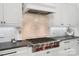Close up of a kitchen with Wolf gas range, marble backsplash and countertops at 8670 Arbor Oaks Cir, Concord, NC 28027