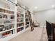 Spacious library featuring floor-to-ceiling bookshelves with rolling ladder and natural light at 8670 Arbor Oaks Cir, Concord, NC 28027