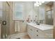 Bathroom featuring a glass shower, a white marble countertop vanity with double sinks, and plantation shutters at 9652 Wheatfield Rd, Charlotte, NC 28277