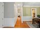 Well-lit hallway with hardwood floors, white wainscoting, and access to multiple rooms, including a view of the kitchen at 9652 Wheatfield Rd, Charlotte, NC 28277