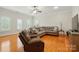 Cozy living room featuring a gray sectional, a recliner chair, and hardwood floors with a window and ceiling fan at 9652 Wheatfield Rd, Charlotte, NC 28277