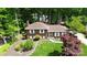 An aerial shot shows the brick home nestled within a canopy of mature trees and expansive lawns at 1024 Regency Dr, Charlotte, NC 28211