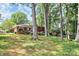 Spacious backyard with mature trees, lush lawn, and a charming brick house exterior, perfect for relaxation at 1024 Regency Dr, Charlotte, NC 28211